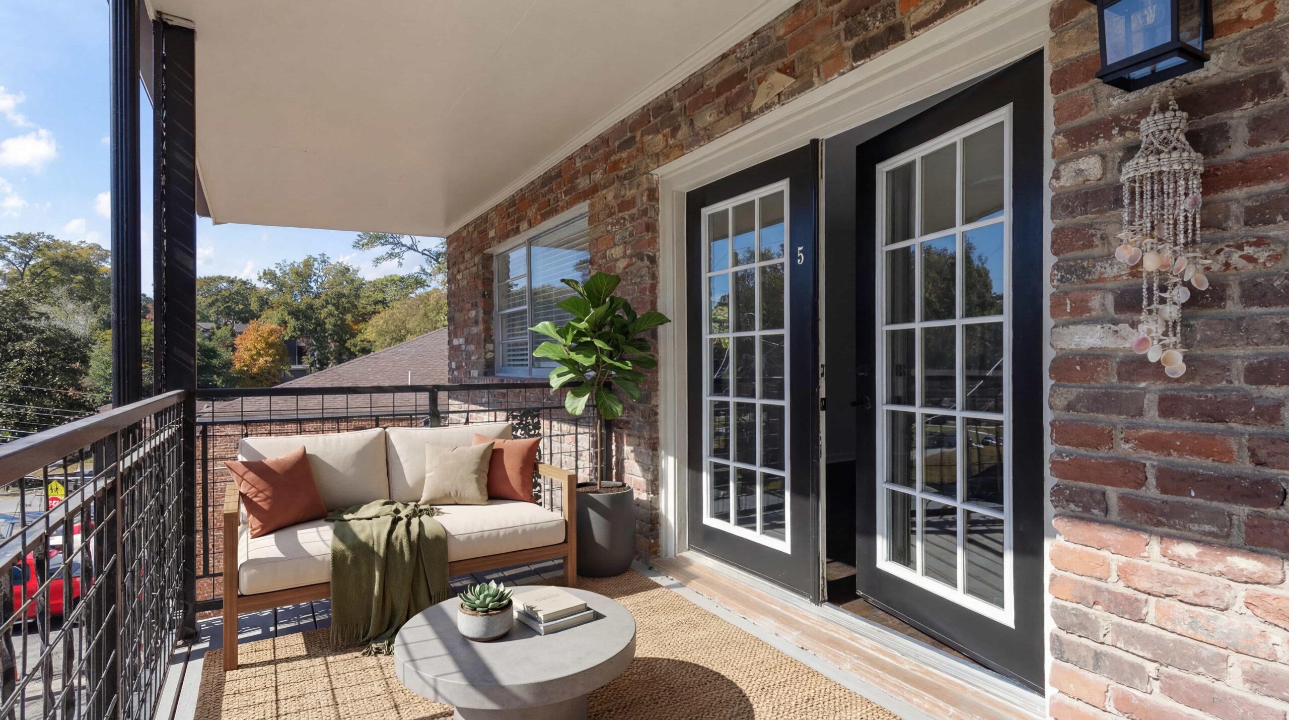 double doors opening to private patio space with sofa outside of apartment